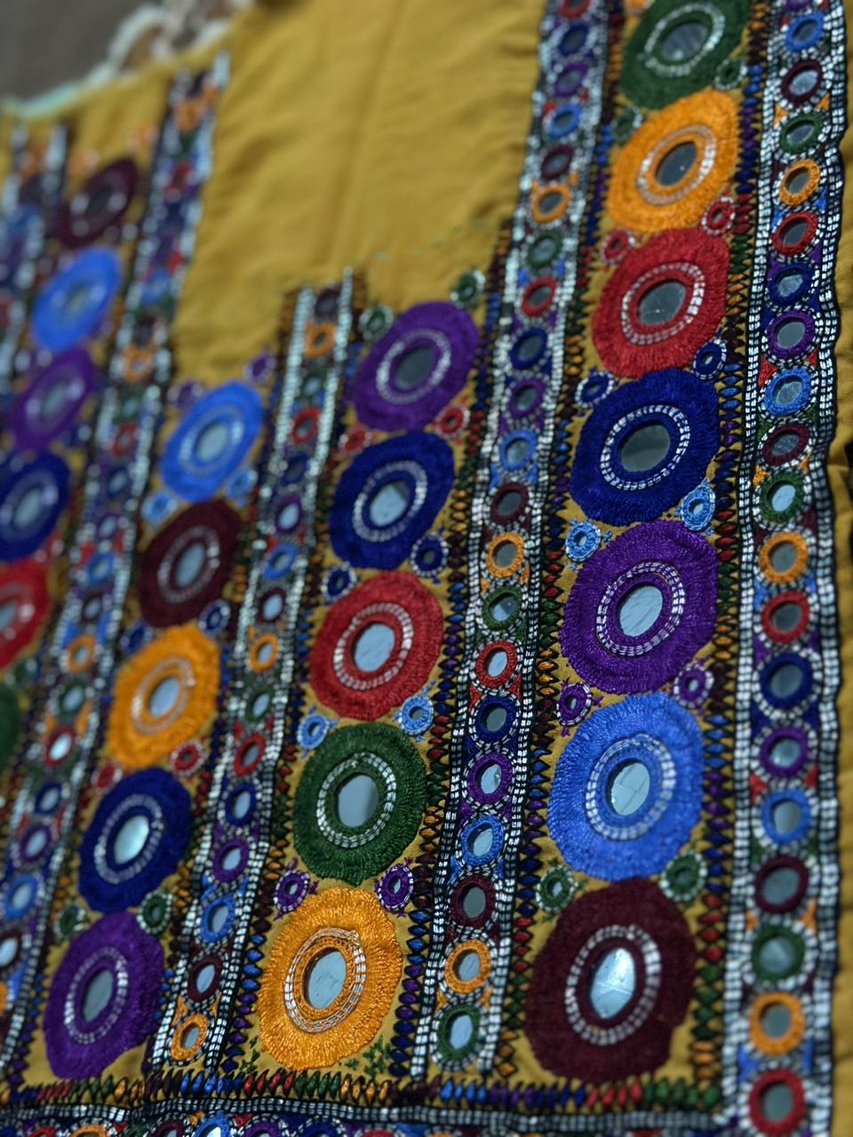 Colorful embroidered fabric that is Handmade and consists of Balochi mirror work embroidery panel on mustard fabric for unstitched kurtis and festive ethnic wear.